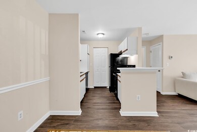 Kitchen with white cabinets, light countertops, dark wood finished floors, premium range hood, and open floor plan