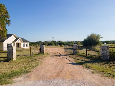 View of dirt / gravel road with a rural view, a gate, and a gated entry