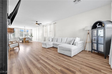 Living room featuring visible vents, ceiling fan w