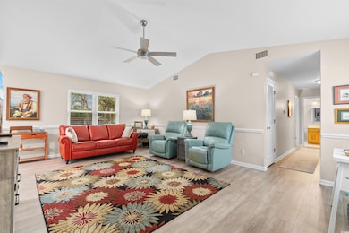 Living room featuring light wood-style flooring, vaulted ceiling, and ceiling fan