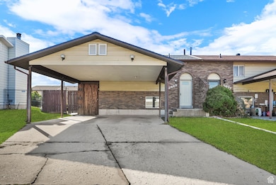 View of front facade featuring brick siding, concrete driveway, and a carport