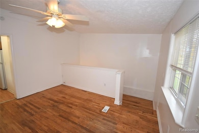 Unfurnished room featuring wood finished floors, a textured ceiling, and ceiling fan