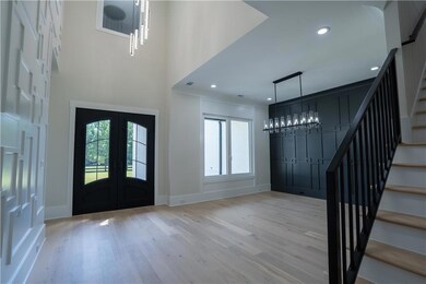 Entryway featuring a chandelier, french doors, stairs, wood finished floors, and recessed lighting