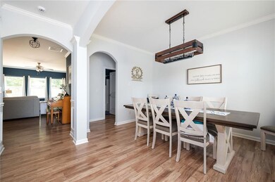 Dining space featuring ceiling fan, light wood finished floors, ornamental molding, and arched walkways