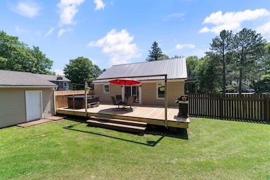 Back of house with a hot tub, a wooden deck, a metal roof, and outdoor dining area