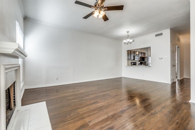 Unfurnished living room featuring dark wood finished floors, a chandelier, crown molding, ceiling fan, and a fireplace