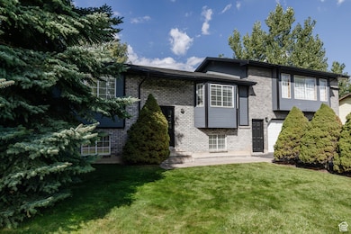 View of front of home with brick siding, a patio area, and a front lawn