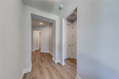 Corridor with light wood-type flooring and recessed lighting