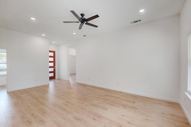 Empty room with ceiling fan, light wood-style floo