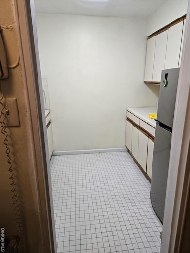 Kitchen featuring white cabinetry and fridge