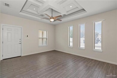 Unfurnished room featuring a tray ceiling, coffered ceiling, light wood-type flooring, and ceiling fan