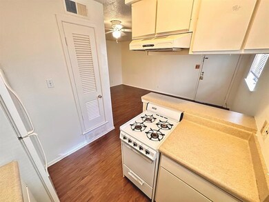 Kitchen with cream cabinets, light countertops, white appliances, dark wood-style floors, and a textured ceiling