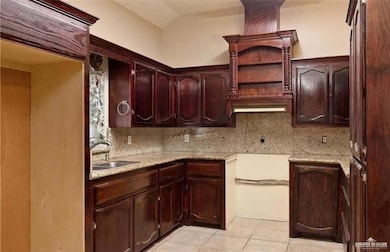 Kitchen with tasteful backsplash, light tile patterned floors, and dark brown cabinets