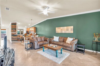 Tiled living room with ceiling fan, crown molding,
