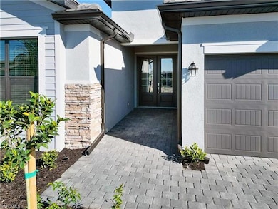 View of exterior entry with stucco siding, a garage, stone siding, and french doors