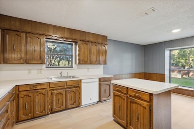 Kitchen with healthy amount of natural light, wooden walls, light wood-type flooring, a wainscoted wall, and light countertops