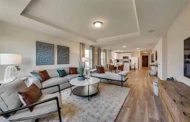 Living area with a raised ceiling, light wood-style flooring, and ornamental molding