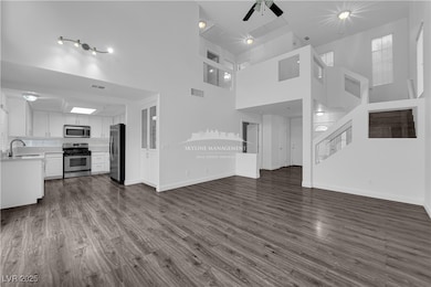 Unfurnished living room featuring a high ceiling, dark wood-type flooring, stairway, and a ceiling fan