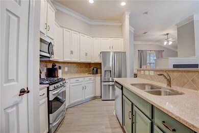 Kitchen featuring stainless steel appliances, ornamental molding, white cabinets, a sink, and green cabinetry