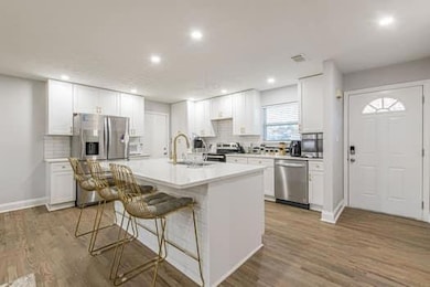 Kitchen with appliances with stainless steel finishes, light wood finished floors, an island with sink, a kitchen breakfast bar, and recessed lighting