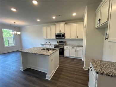 Kitchen with appliances with stainless steel finishes, crown molding, a chandelier, dark wood-style floors, and white cabinetry