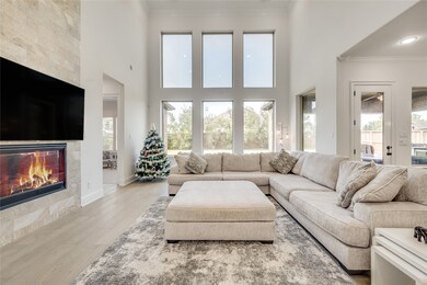 This living room is more like a GREAT room featuring a stunning fireplace with mantel detailing, custom paint, soaring high ceiling, recessed lighting, dark stained ceiling fan, wood flooring and an amazing wall of windows providing a lovely view of your backyard to keep an eye out on the kids or pets playing.

