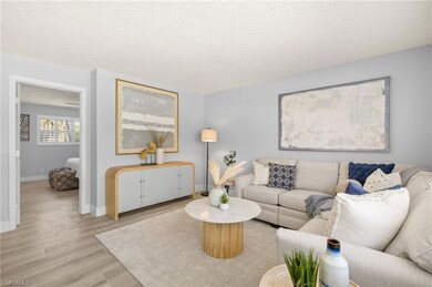 Living room featuring light wood-type flooring, baseboards, and a textured ceiling