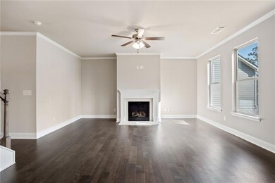 Unfurnished living room with dark wood finished floors, crown molding, ceiling fan, and a fireplace