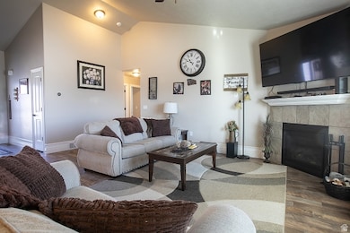 Living area featuring wood finished floors, a tiled fireplace, and high vaulted ceiling