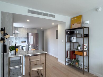 Kitchen featuring freestanding refrigerator, light wood-style flooring, a peninsula, recessed lighting, and wall chimney range hood