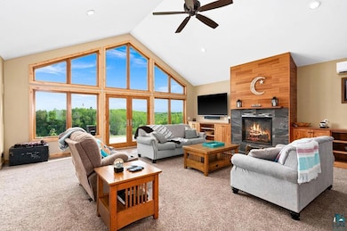Living room with light colored carpet, ceiling fan, a high end fireplace, recessed lighting, and high vaulted ceiling