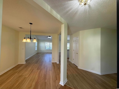Additional living space featuring a chandelier, wood finished floors, a textured ceiling, and a ceiling fan