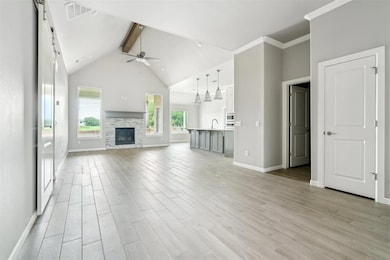 Unfurnished living room featuring beamed ceiling, a ceiling fan, light wood-style flooring, a fireplace, and high vaulted ceiling