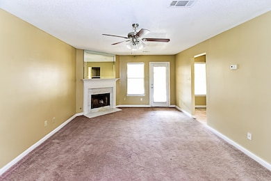 Unfurnished living room featuring carpet, a fireplace, a ceiling fan, and a textured ceiling