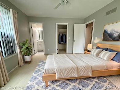 Carpeted bedroom with a spacious closet and ceiling fan