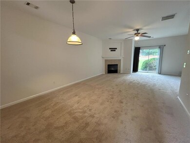 Unfurnished living room featuring light carpet, ceiling fan, and a tiled fireplace