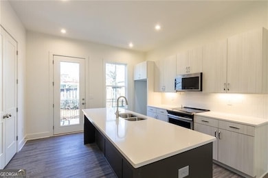 Kitchen featuring a sink, light countertops, an island with sink, and appliances with stainless steel finishes