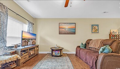 Living room featuring dark wood-type flooring, baseboards, and ceiling fan