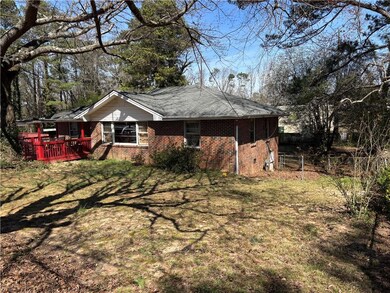 View of side of home with a wooden deck, a lawn, a