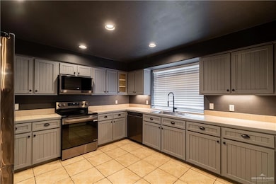 Kitchen with appliances with stainless steel finishes, light tile patterned floors, recessed lighting, gray cabinetry, and tile countertops