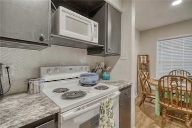 Kitchen with white appliances, backsplash, light w