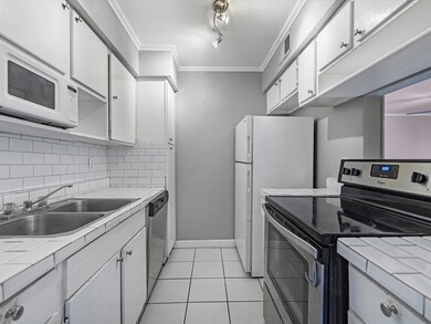 A galley kitchen featuring white cabinetry, white