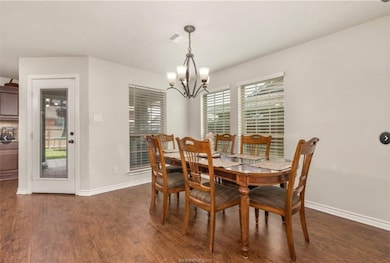 Dining area with dark wood-style flooring and a chandelier
