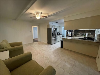 Living room with ceiling fan, beam ceiling, and light tile patterned floors