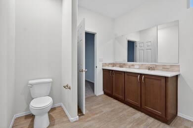 Full bath featuring double vanity and light wood-style flooring