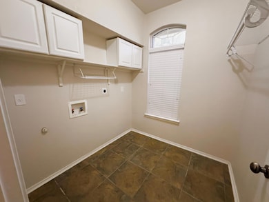 Washroom with cabinet space, hookup for an electric dryer, washer hookup, and dark tile patterned flooring