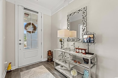 Foyer entrance with crown molding and dark hardwoo
