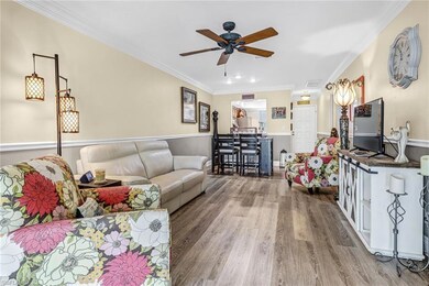 Living room with crown molding, ceiling fan, and h