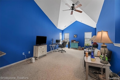 Carpeted office with high vaulted ceiling and a ceiling fan