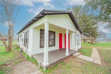 View of side of home with fence, a porch, and a ya